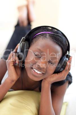 Cute woman listening music with headphones lying on a sofa