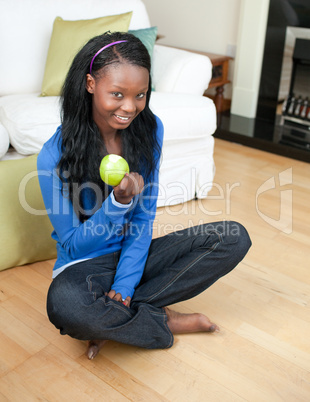 Happy woman eating an apple sitting on the floor
