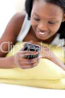 Afro-american woman sending a text lying on a sofa