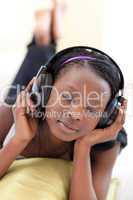 Pretty woman listening music with headphones lying on a sofa