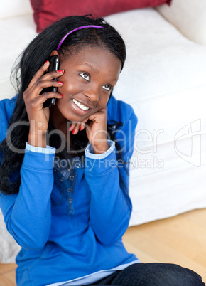 Pretty young woman talking on phone sitting on the floor