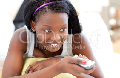 Bright young woman watching TV lying on a sofa