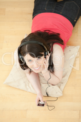 Merry woman listening music lying down on the floor