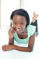 Smiling teen girl using a mobile phone lying on her bed