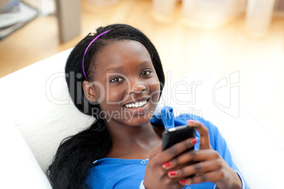 Bright woman sending a text lying on a sofa