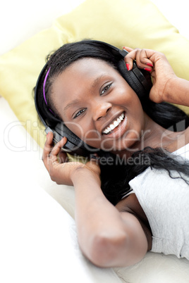 Jolly woman listening music with headphones lying on a sofa