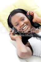 Jolly woman listening music with headphones lying on a sofa