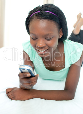 Cute teen girl using a mobile phone lying on her bed