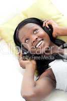 Joyful woman listening music with headphones lying on a sofa