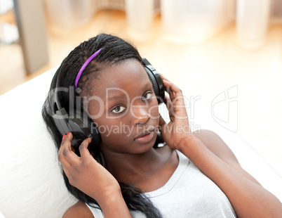 Beautiful woman listening music with headphones lying on a sofa