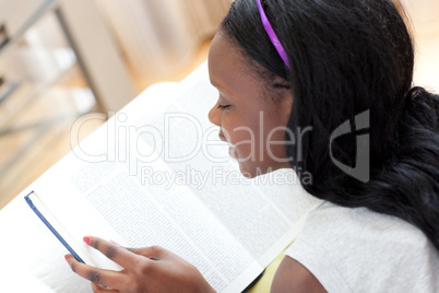 Cheerful teen girl studying lying on a sofa