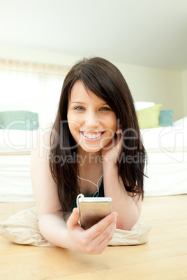Laughing woman listening music lying on the floor