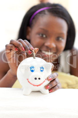 Happy teen girl putting money in a piggy-bank