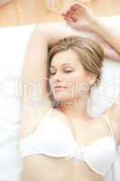 Dreamy woman in underwear lying on bed