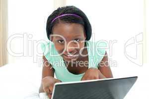 Charming woman using a laptop lying on her bed