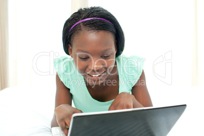Young woman using a laptop lying on her bed