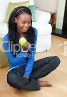 Jolly woman eating an apple sitting on the floor