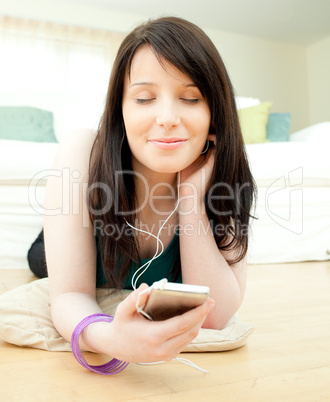 Dreamy woman listening music lying on the floor