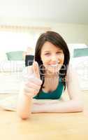 Happy woman with thumbs up lying on the floor