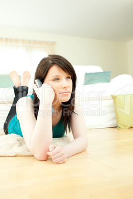 Delighted woman watching television lying down on the floor