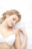 Asleep woman in underwear lying on bed