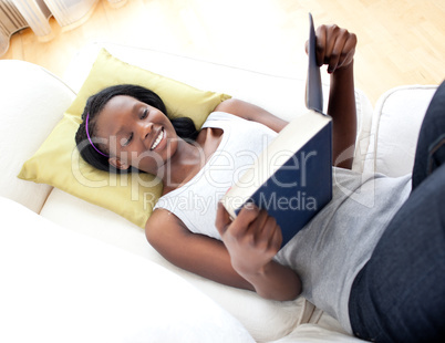 Smiling woman reading lying on a sofa