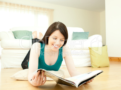 Smiling woman reading a magazine lying down on the floor