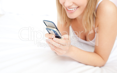 Close-up of a blond woman giving a text message lying down on be