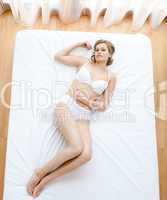 Blond woman in underwear lying on bed