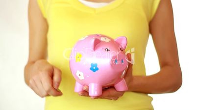 Hand inserting coins into piggy bank