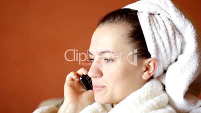 Young attractive woman in a bathrobe talking on cell phone