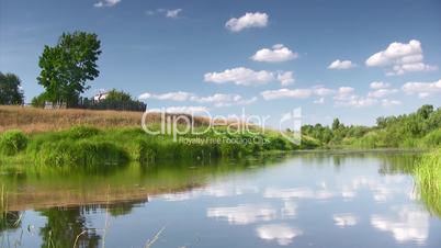 Rural landscape with river,lone tree and clouds