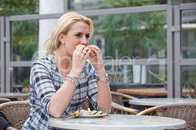 Pretty blond girl eating a bagel