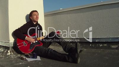 A man sitting on the floor and plays guitar