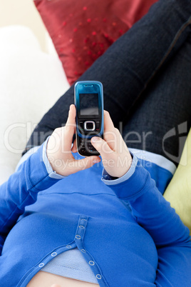 Close-up of a teen girl sending a text lying on a sofa