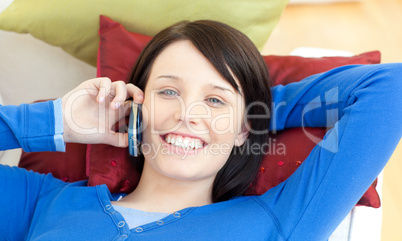 Charming teen girl talking on phone lying on a sofa