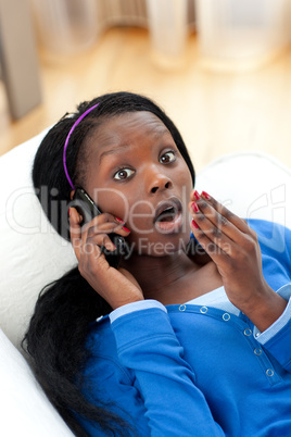 Surprised woman on phone lying on a sofa