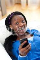 Cheerful woman sending a text lying on a sofa