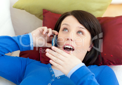 Surprised teen girl talking on phone lying on a sofa