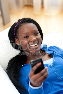 Jolly woman sending a text lying on a sofa