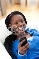 Jolly woman sending a text lying on a sofa