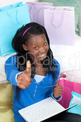 Smiling teen girl with thumb up shopping on-line
