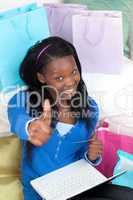 Smiling teen girl with thumb up shopping on-line