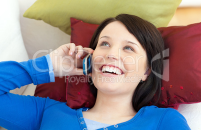Happy teen girl talking on phone lying on a sofa