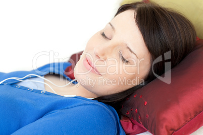 Relaxed young woman listening music lying on a sofa