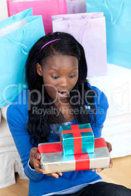 Surprised woman holding a present sitting on the floor