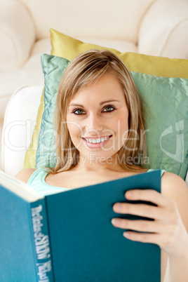 Charming woman reading a book lying on a sofa