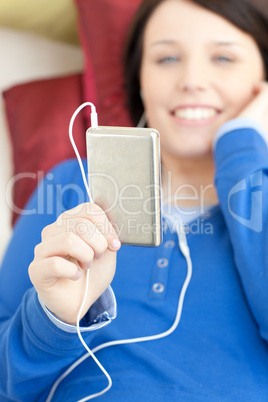 Cute young woman listening music lying on a sofa