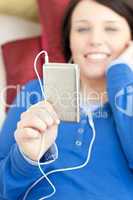 Cute young woman listening music lying on a sofa