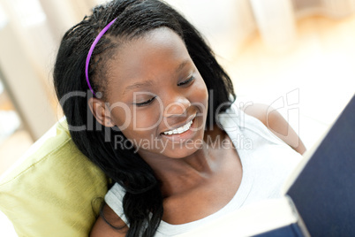 Smiling woman reading a book lying on a sofa